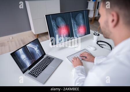 Reife männliche Arzt untersuchen Knie X-ray In der Klinik Stockfoto