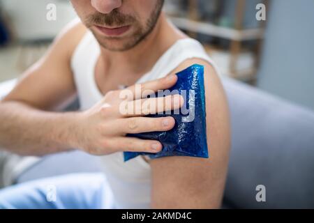 Nahaufnahme eines Mannes Anwendung Cool Gel Pack auf seiner Schulter Stockfoto