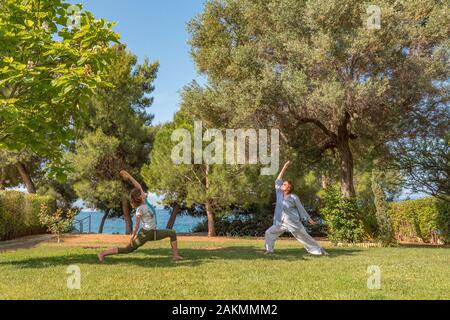 Yoga, Krieger darstellen. Zwei Frauen Yoga auf Hinterhof, Vorplatz. Gesunder Lebensstil Konzept. Morgen körperliche Aktivitäten im Park, Hinterhof. Happ Stockfoto