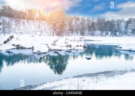 Sehenswürdigkeiten in den Bergen des Altai, blaue Seen nicht Einfrieren im Winter um Steine mit grünem Schlamm bedeckt mit Schnee, in denen Bäume und Himmel sind refle Stockfoto