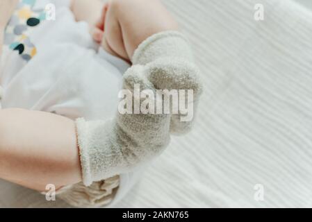 Baby Beine. Crawling Baby in weißen Socken und Body. Blick von oben. Stockfoto