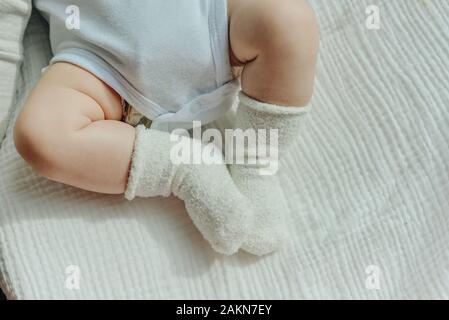 Baby Beine. Crawling Baby in weißen Socken und Body. Blick von oben. Stockfoto