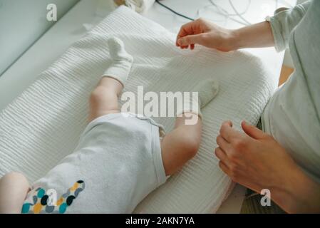 Baby Beine. Crawling Baby in weißen Socken und Body. Blick von oben. Stockfoto