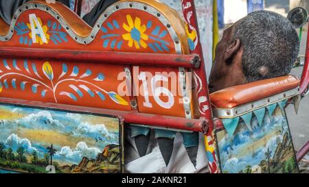 KOLKATA, West Bengal/INDIEN - 19. MÄRZ 2018: ein Zyklus Rikscha Fahrer döst in seinem bunten Wagen auf den Straßen von Kalkutta. Stockfoto