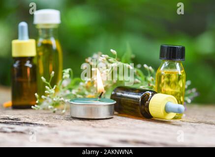 Aromatherapie pflanzliche Öl Flaschen Aroma mit blume Blätter pflanzliche Formulierungen einschließlich Wildblumen und Kräutern auf Holz / Duftkerzen ätherische Öle Stockfoto