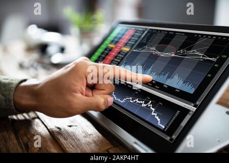 Nahaufnahme eines Stock Market Research Hand in Diagrammen auf Laptop Stockfoto