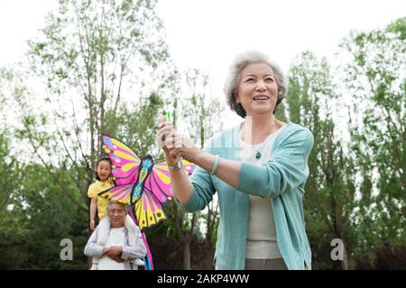 Ältere Paare mit einer Enkelin ist Flying a Kite im Park Stockfoto