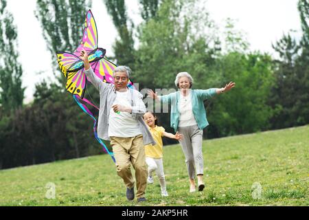 Ältere Paare mit einer Enkelin ist Flying a Kite im Park Stockfoto