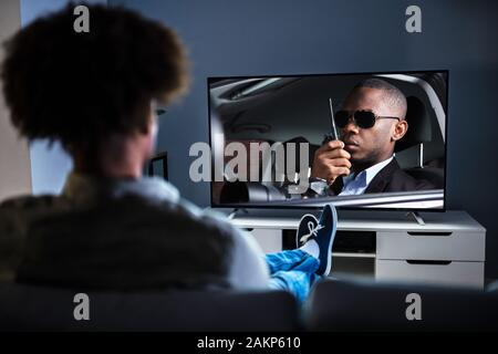 Afrikanischer Mann auf Sofa mit Fernbedienung In der Hand Stockfoto