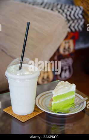 Milch-Smoothie mit Kokoskuchen auf Glastisch Stockfoto