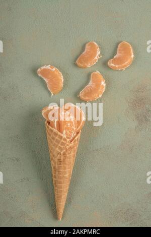 Tangenine Frucht in Eiskegel auf grünem Hintergrund mit Kopierraum, flacher Lay Stockfoto