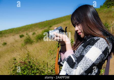 Reisende von Frauen machen ein Foto mit Digitalkamera auf gelbem Grashintergrund Stockfoto