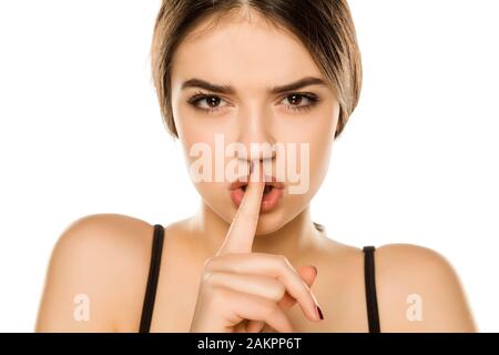 Porträt der schönen jungen Frau mit Finger auf ihre Lippen auf weißem Hintergrund Stockfoto