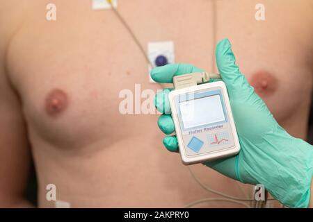 Die Hand des Arztes, der holter-herzmonitor auf die Brust eines jungen Mannes aufgibt Stockfoto