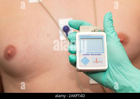 Die Hand des Arztes, der holter-herzmonitor auf die Brust eines jungen Mannes aufgibt Stockfoto