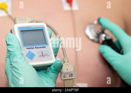 Die Hand des Arztes, der holter-herzmonitor auf die Brust eines jungen Mannes aufgibt Stockfoto