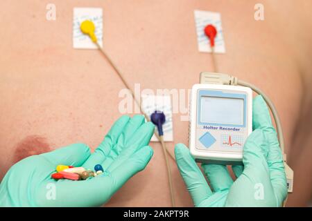 Die Hand des Arztes, der holter-herzmonitor auf die Brust eines jungen Mannes aufgibt Stockfoto