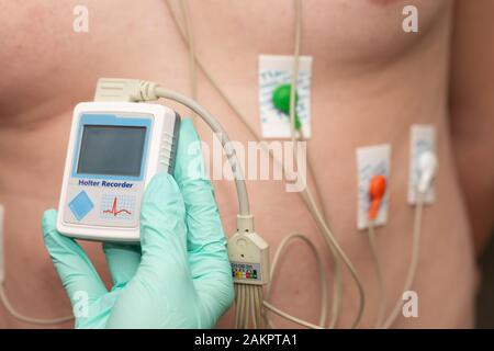 Die Hand des Arztes, der holter-herzmonitor auf die Brust eines jungen Mannes aufgibt Stockfoto