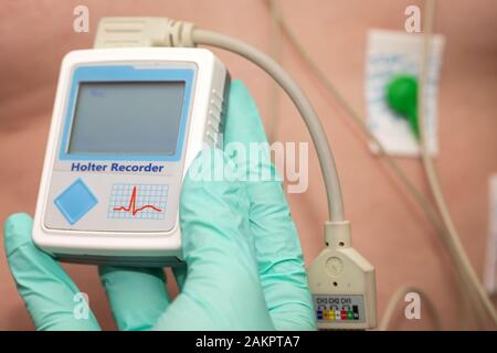 Die Hand des Arztes, der holter-herzmonitor auf die Brust eines jungen Mannes aufgibt Stockfoto