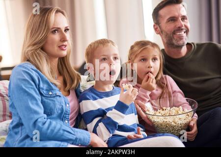 Familie mit zwei Kindern vor dem Fernseher im Wohnzimmer Stockfoto