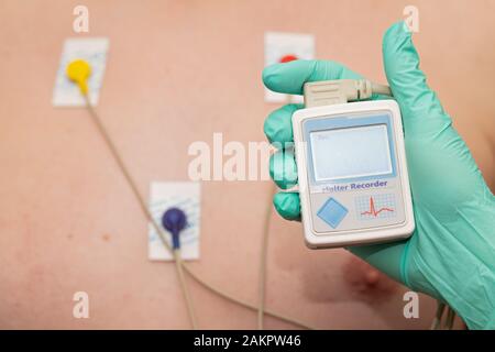 Die Hand des Arztes, der holter-herzmonitor auf die Brust eines jungen Mannes aufgibt Stockfoto