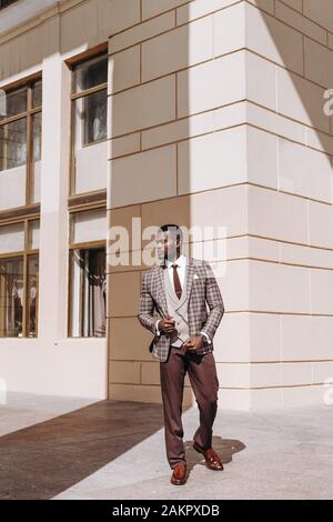 Ganzkörperporträt von afrikanisch-amerikanischen Modelmodellen in einem braunen Anzug. Stilvoller Luxus teurer Business-Look, gut gekleideter Gentleman Stockfoto