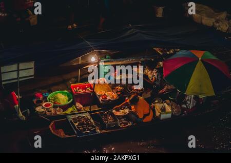 Händler, die in Amphawa nachts in Dunkellicht Lebensmittel verkaufen, dem berühmtesten schwimmenden Markt und kulturellen Touristenziel am 6. April 20 Stockfoto