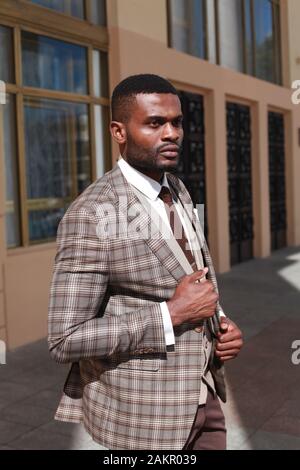 Ganzkörperporträt von afrikanisch-amerikanischen Modelwand-Modell-Walking und in einem braunen Anzug. Stilvoller Luxus teurer Business-Look, gut gekleideter Gentleman Stockfoto
