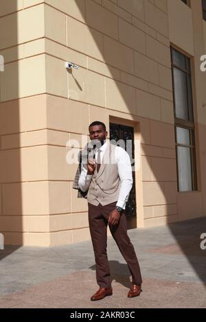 Ganzkörperporträt von afrikanisch-amerikanischen Modelwand-Modell-Walking und in einem braunen Anzug. Stilvoller Luxus teurer Business-Look, gut gekleideter Gentleman Stockfoto