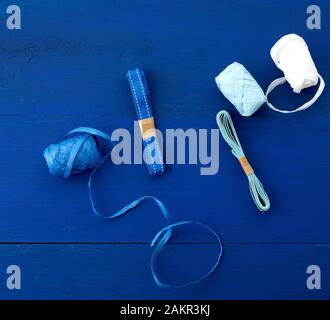 Verschiedene Farbbänder für Geschenkverpackungen auf blauem Holzhintergrund, Draufsicht Stockfoto