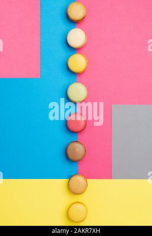 Klassische französische Dessert. Bunte macarons auf kreative Rosa Grau Blau Gelb Hintergrund angeordnet, selektiver Fokus Stockfoto