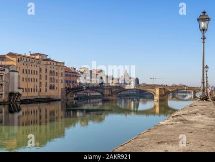 Florenz, Italien, 6. Januar 2020: Der Fluss Arno im Winter die Sonne. Als sie die Brücke Ponte Santa Trinita Es ist die älteste elliptisch Bogenbrücke in der Bekannten Stockfoto