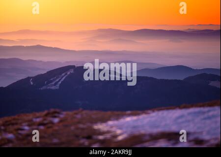 Wunderschönes, weiches orangefarbenes Morgenlicht in den Bergen, späte Winterlandschaft mit erstem Schnee. Stockfoto