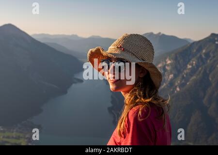 Junge Frau mit Sonnenbrille und Sonnenhut, in der Rückseite Berglandschaft mit der Achensee, Ansicht vom Berg Baerenkopf, Tirol, Österreich Stockfoto