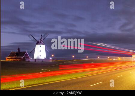 Lytham, Lancashire. UK Wetter. 10 Jan, 2020. gedeckten Farben bei dawnm und verschwommene Lichter vom Verkehr leavig rote Spuren, nach einer kalten Nacht auf die fylde Coast. Lytham Windmühle als sonnenaufgänge auf Lytham Grün in der Küstenstadt Lytham St Annes, Lancashire, England. Es ist von der Art wie ein Tower Mill bekannt und wurde für das Schleifen von Weizen und Hafer Mehl oder Kleie entworfen. Kredit; MediaWorldImages/AlamyLiveNews Stockfoto