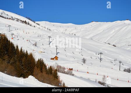 Les Sybelles Skigebiet in Frankreich - Blick auf lange Sessellifte und Pisten, an einem blauen Himmelstag. Stockfoto