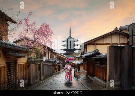 Asiatische junge Frau Reisenden tragen traditionelle japanische Kimono mit roten Regenschirm Sightseeing in berühmten Ziel Sannen Zaka Straße mit historischen Stockfoto