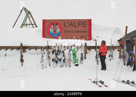 Les Sybelles, Frankreich - 14. März 2019: Skifahrer in der Nähe eines Skiracks an der Berghütte L'Alpe bei starkem Schneefall im Skigebiet Les Sybelles. Stockfoto