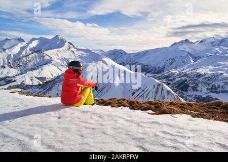 Frau Skifahrerin, die die Berggipfel in den französischen Alpen, auf der Skidomäne Les Sybelles, oberhalb des Dorfes Saint-Jean-d'Arves, Frankreich, betrachtet. Winter-Freizeitangebot Stockfoto