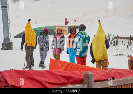 Les Sybelles, Frankreich - 14. März 2019: Lustige, gekleidete Skifahrer, die Bananen-, Zebra- und hawaiianische Kostüme tragen, während eines Whiteout blizzards in Les Sybelles s Stockfoto