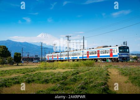 Ein Zug der JR Izuhakone Tetsudo-Sunzu Line reisen durch die Landschaft an einem sonnigen Frühlingstag und Mt. Fuji in Mishima, Shizuoka, Japan. Rai Stockfoto