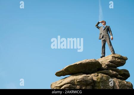 Unternehmer sich auf einem felsigen Gipfel mit Blick in den blauen Himmel Platz kopieren Stockfoto