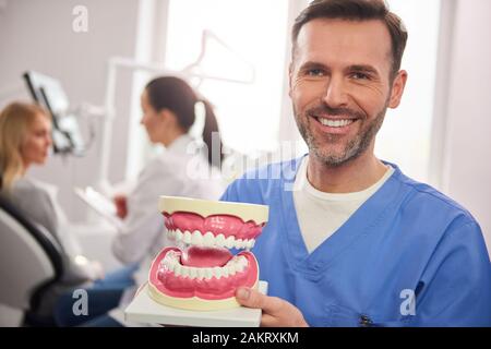 Lächelnd Zahnarzt zeigt eine künstliche Gebisse Stockfoto
