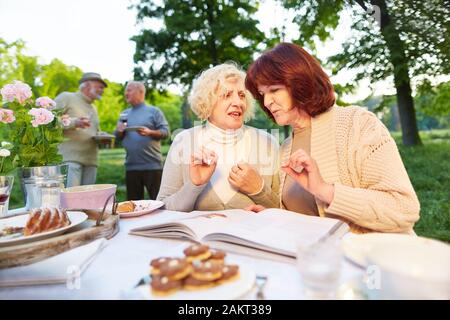 Senioren sprechen über Buch bei Feier im Sommer im Garten Stockfoto