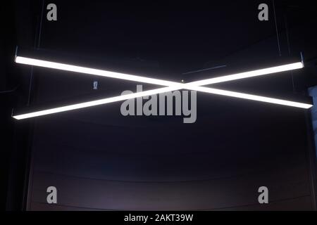 Moderne Bürobeleuchtung. Dünne Lampen in Office dunklen Decke. LED Weiß kaltes Licht über Arbeitsplätze. Stockfoto