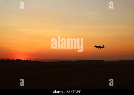 Silhouette eines Flugzeuges, das zum Himmel bei Sonnenuntergang abfliegt Stockfoto