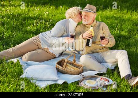 Zwei seniors Küssen an einem Picknick im Sommer auf einer Wiese Stockfoto