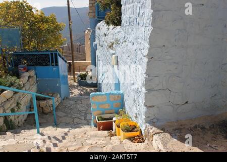 Getrocknete Pflanzen und Blumen wachsen in Plastikblütentöpfen neben der Marmortreppe eines zerstörten alten Steinhauses in einer antiken Stadt Stockfoto