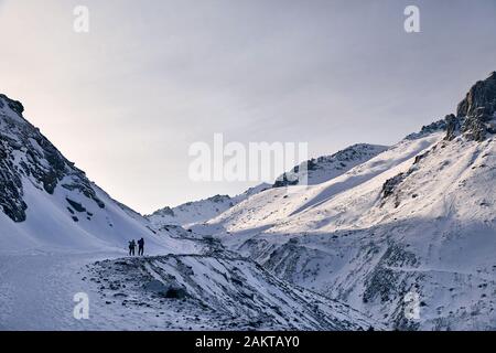 Zwei Wanderer sind Klettern auf der Strecke in der Nähe der Gletscher gegen den blauen Himmel Hintergrund. Outdoor Klettern und Bergsteigen Konzept. Stockfoto