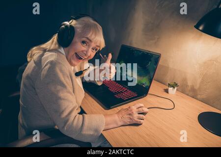 Portrait von ihr schöne fröhliche, grauhaarige blonde Oma Spiel mit Daumen Ratschlag Wettbewerb Kampf Meisterschaftsgewinn bei Industrial Stockfoto